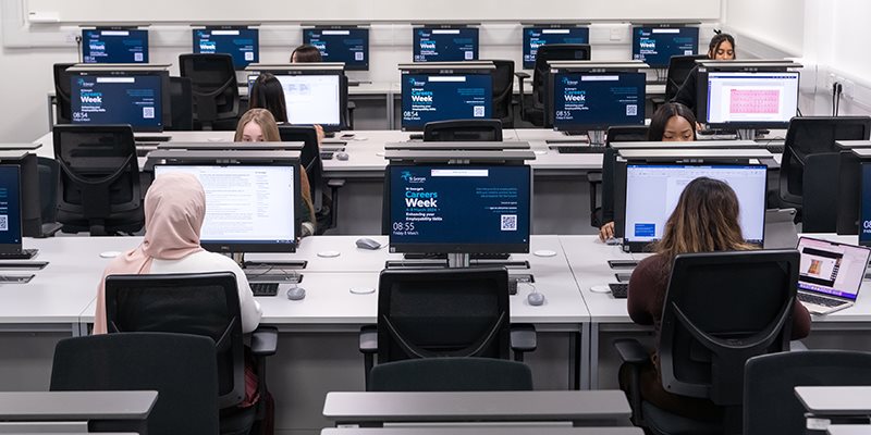 Students using computers sat at desks in computer room