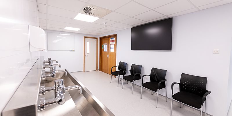 Lobby area in simulation hospital setting with seating area, scrub trough and TV mounted on wall above chairs