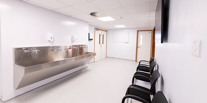 Lobby area in simulation hospital setting with seating area, scrub trough and TV mounted on wall above chairs