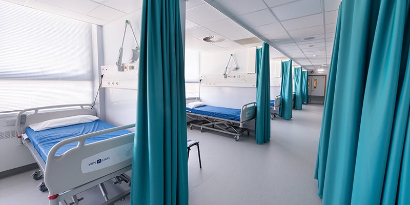 Hospital beds in bays, separated by privacy curtains, in simulation hospital setting