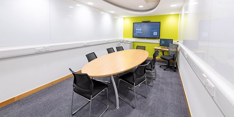 Empty base room with chairs round table in front of digital screen mounted on wall