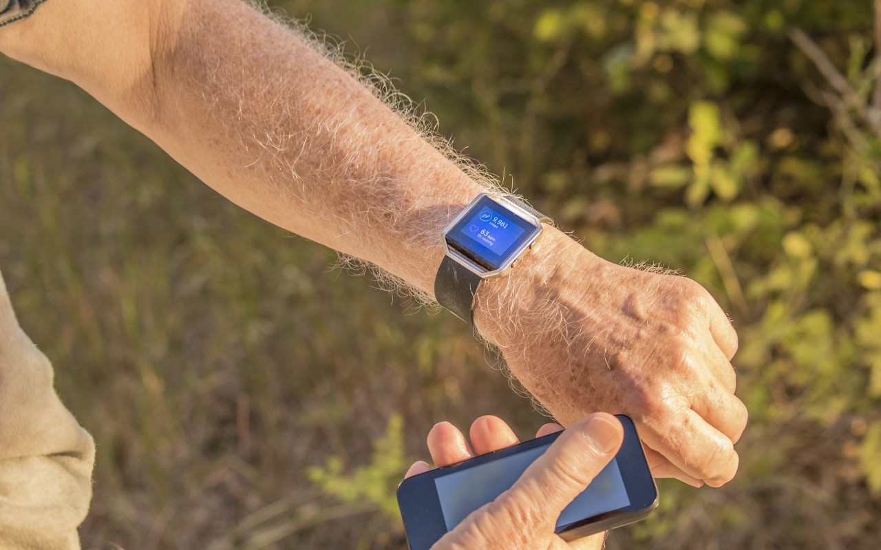 Man with smart watch and mobile phone looking at pedometer results