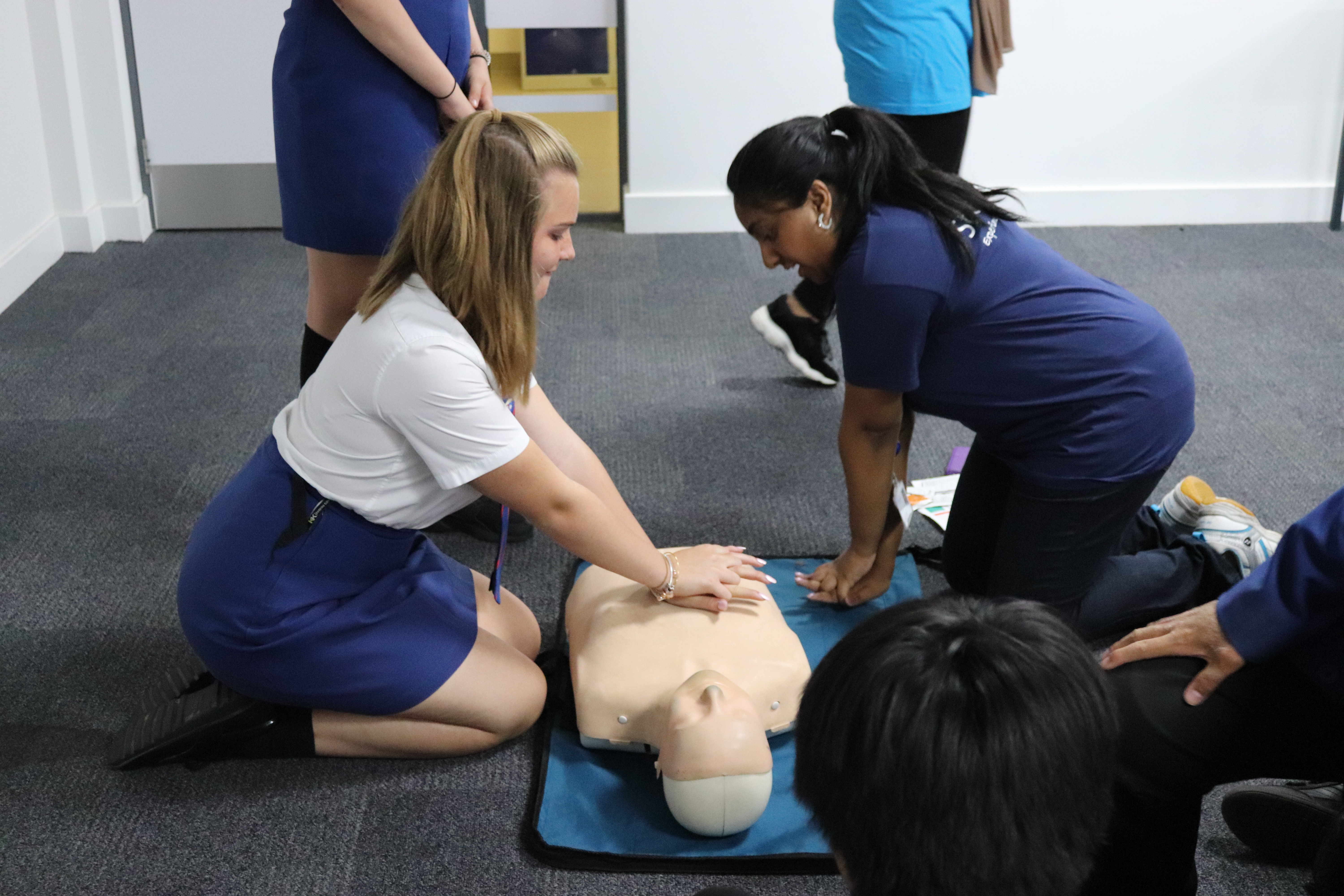 Tutors teaching CPR to secondary school students. 