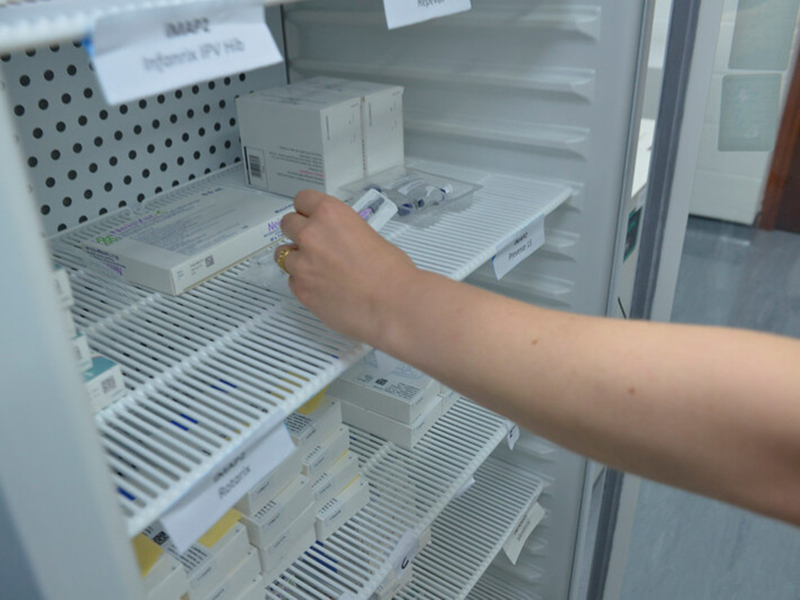 Hand placing vaccine in fridge in laboratory