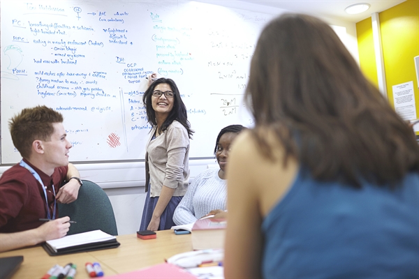 A student writes on the whiteboard during a class.